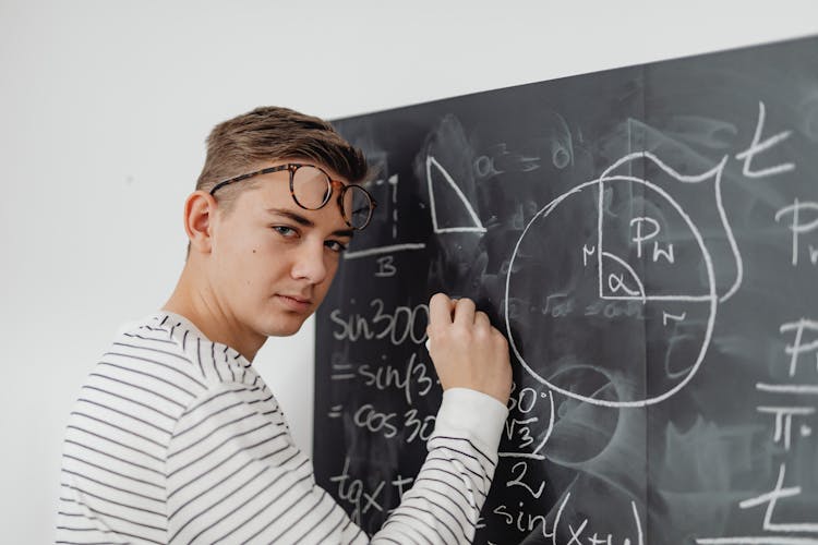 Boy Writing An Equation On A Blackboard 