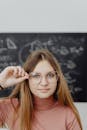 Portrait of a Young Woman in Eyeglasses in front of a Blackboard