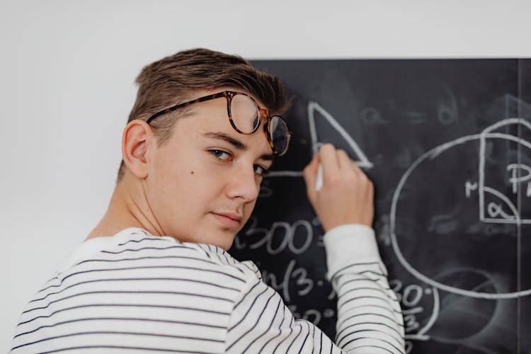 Teenage Boy Writing On A Chalkboard