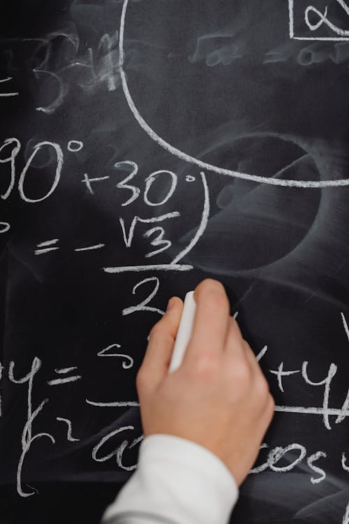 Close-up of a Person Solving and Equation on a Blackboard 