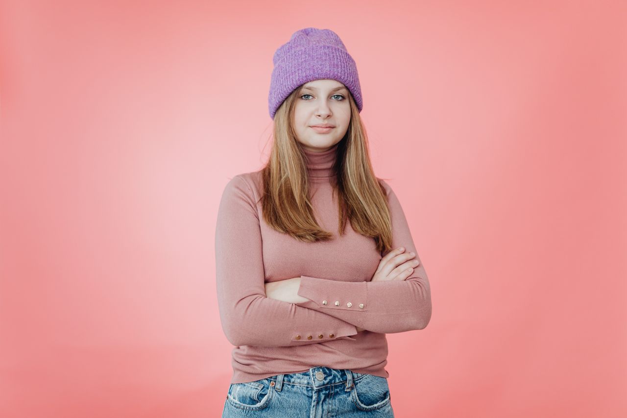 Woman in a pink turtleneck sweater, jeans and purple beanie