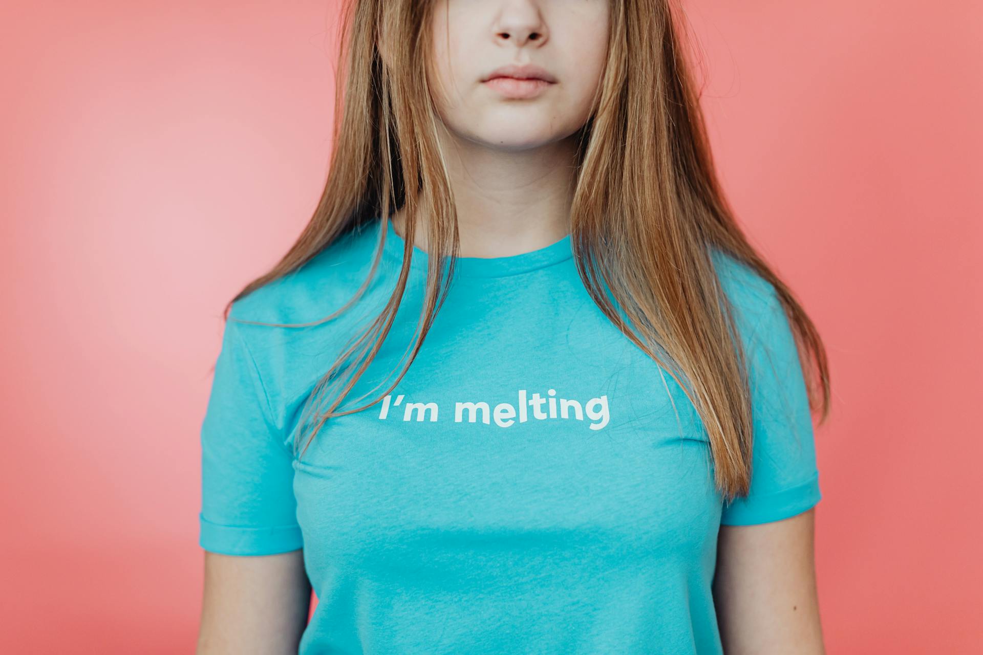 Close-up of a woman in blue shirt with 'I'm melting' text on a pink background.