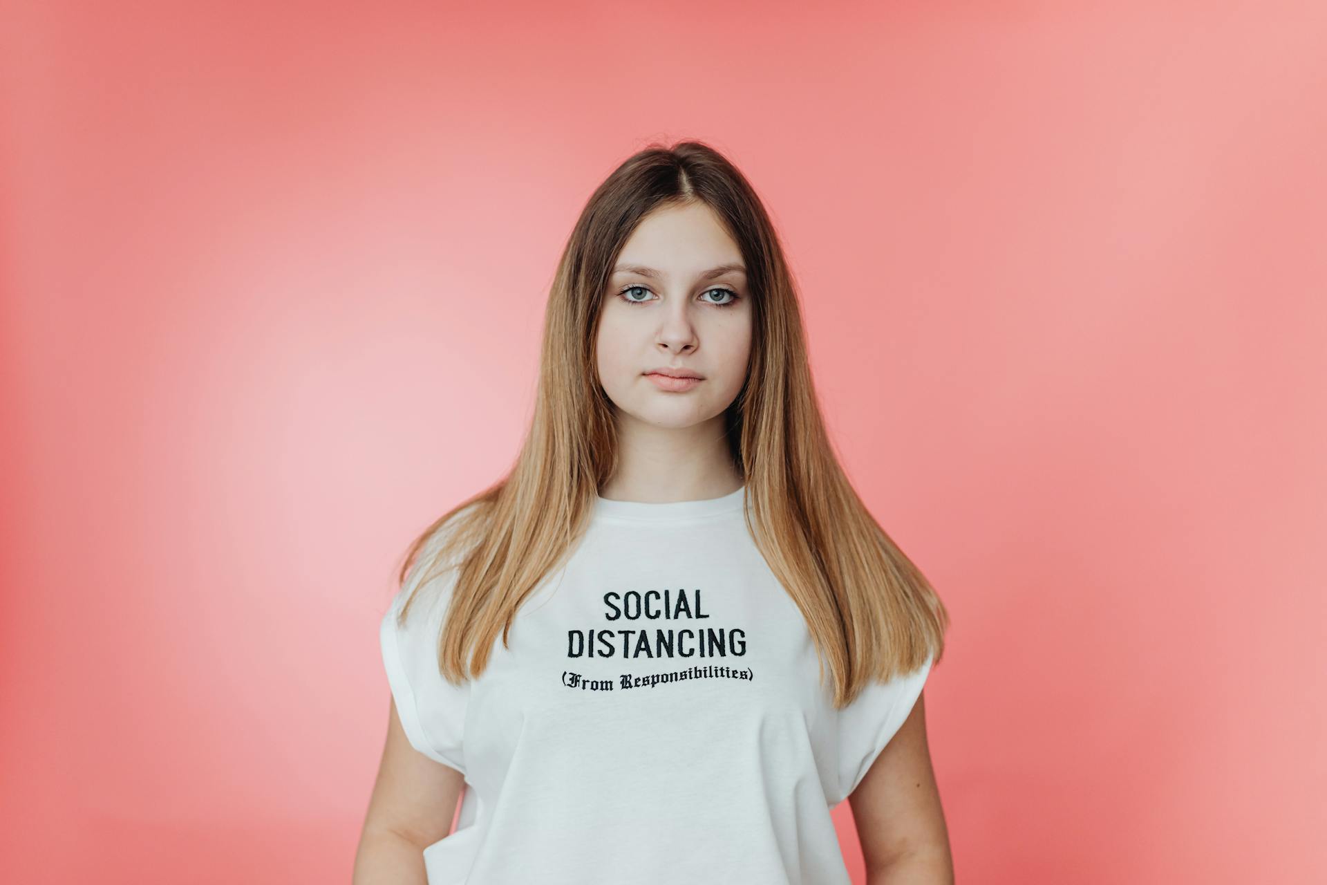 Portrait of a young woman in a t-shirt with a humorous text about social distancing.