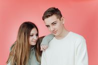 Young Man in White Shirt Standing Beside a Woman in Gray Hoodie