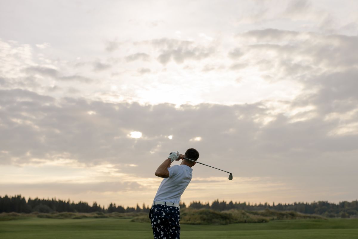 Golfer holding a balanced finish at sunset