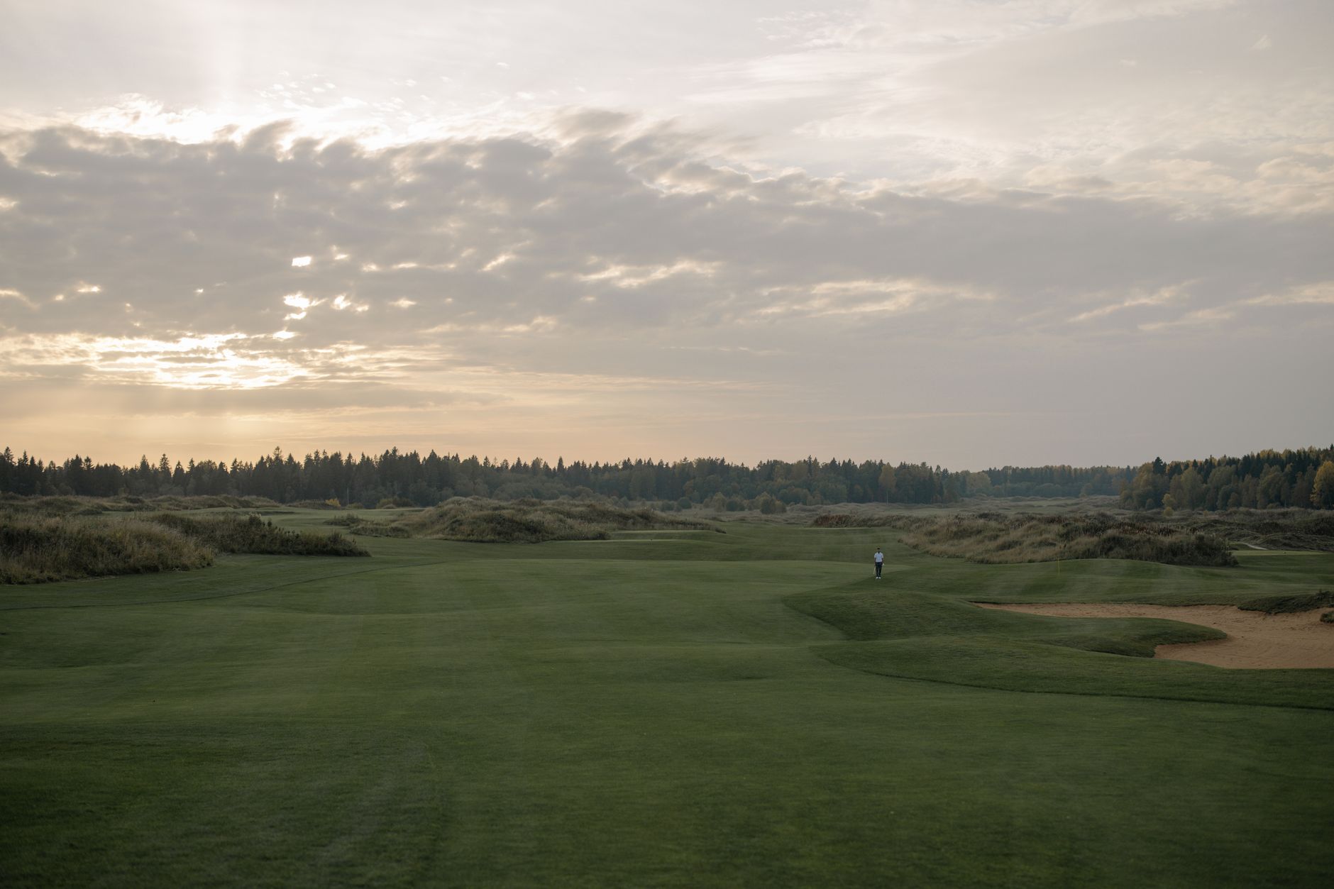 A breathtaking aerial view of a coastal luxury golf resort at sunset, highlighting the sensory beauty of the fairway.