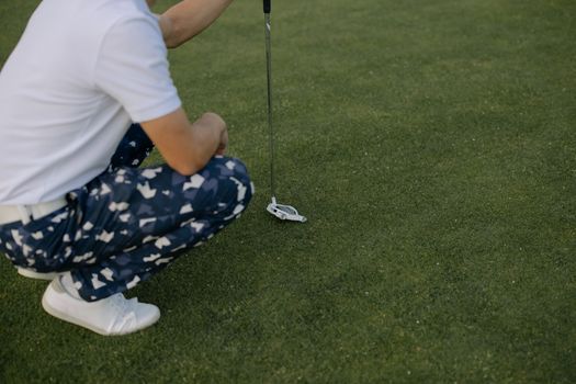 Person in White T-shirt and Blue and White Pants Holding Golf Club