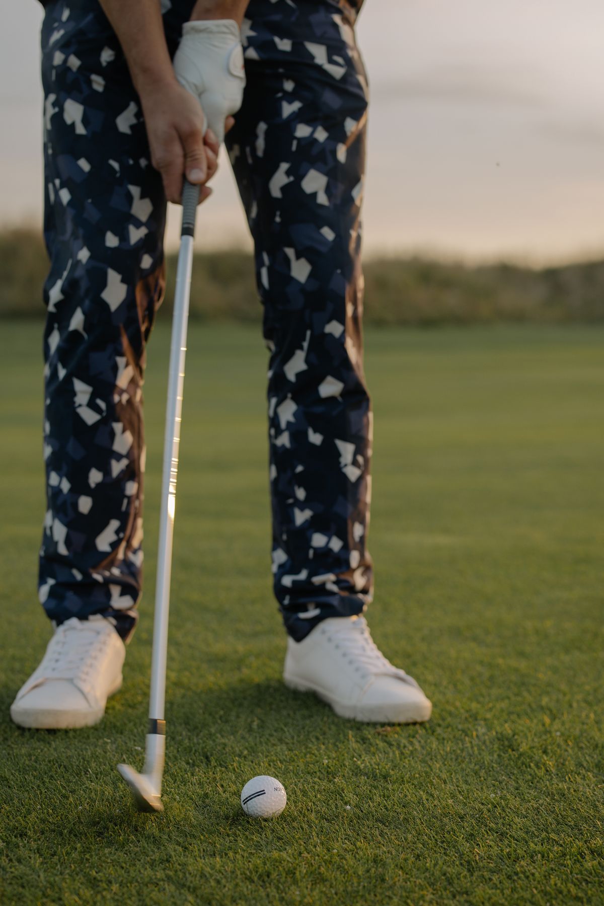 Golfer at address with an iron behind the ball on the fairway