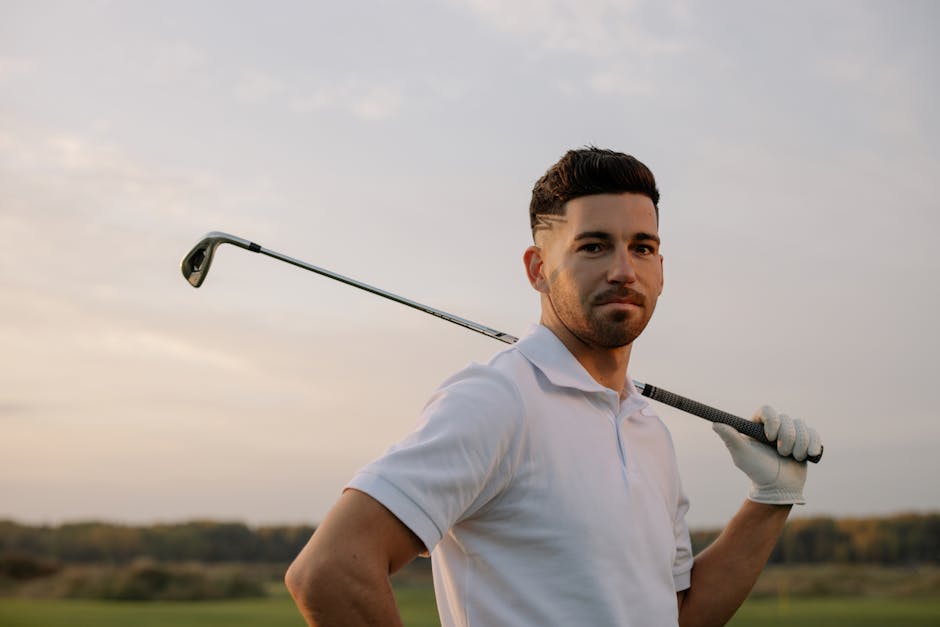 Confident male golfer posing with club at sunset, exuding style and skill.