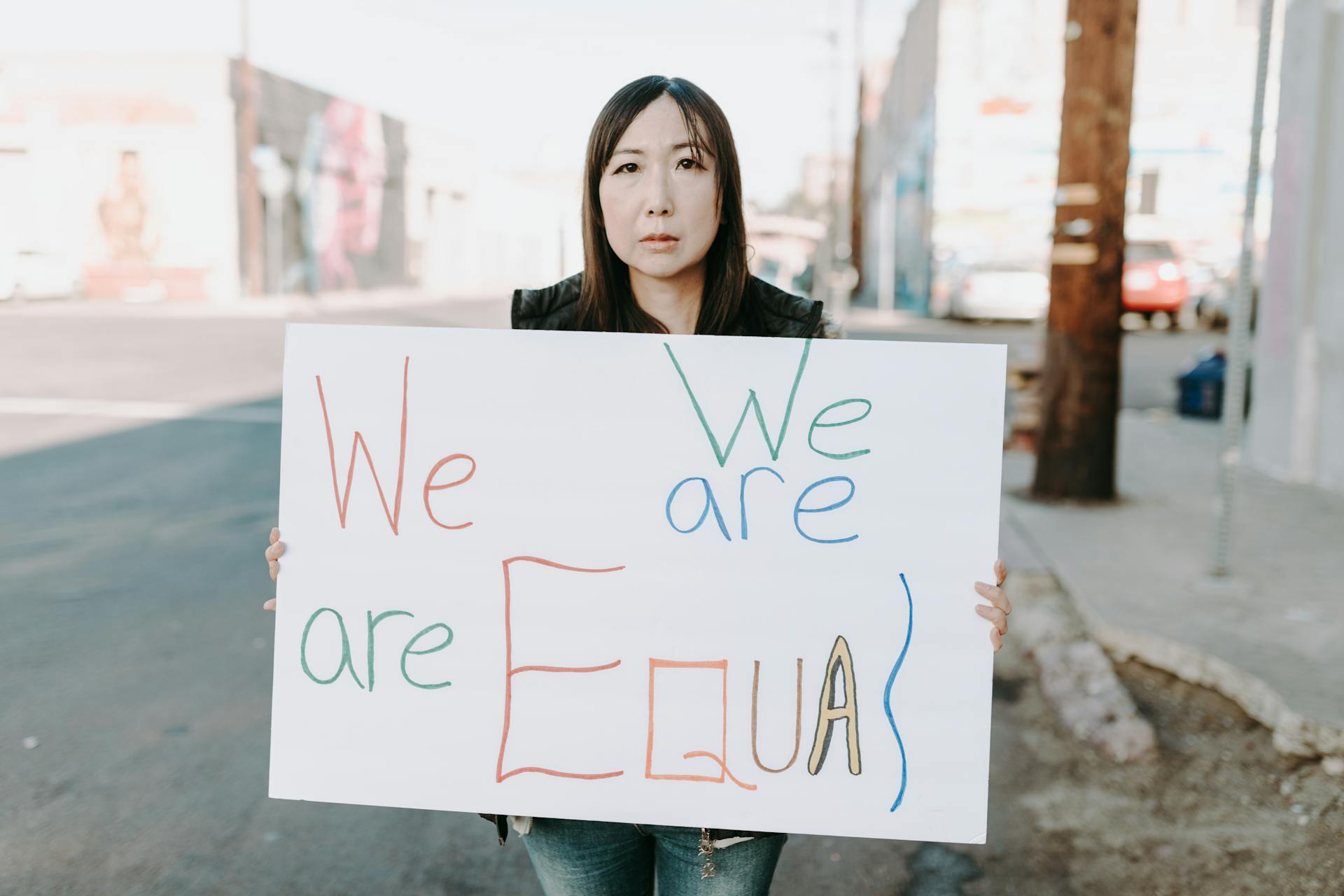 Empowering image of an Asian woman holding a sign promoting equality during a street protest.