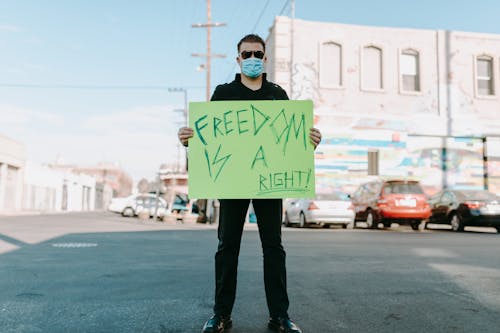 Man Standing on the Street Holding a Poster