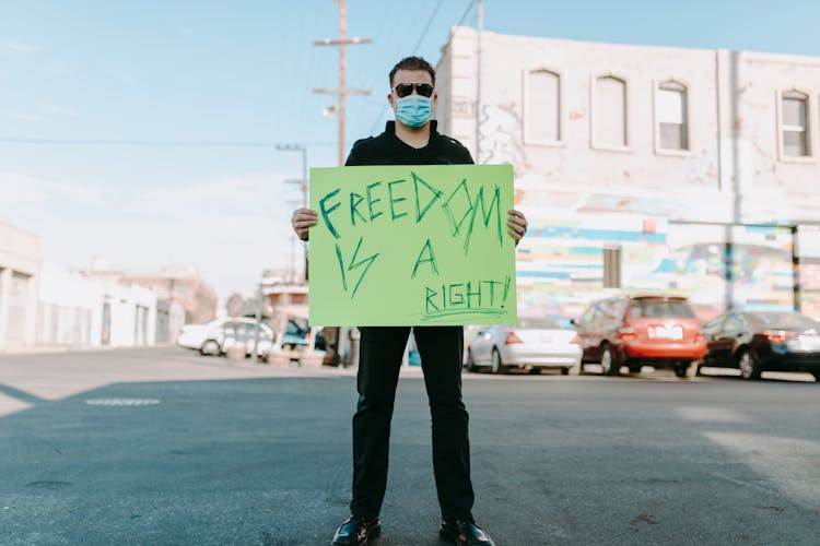 Man Standing On The Street Holding A Poster