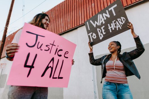 Two individuals holding protest signs advocating for justice and equality in an outdoor setting.