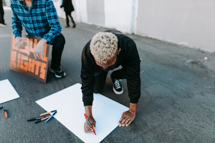 A Man Writing On A Poster