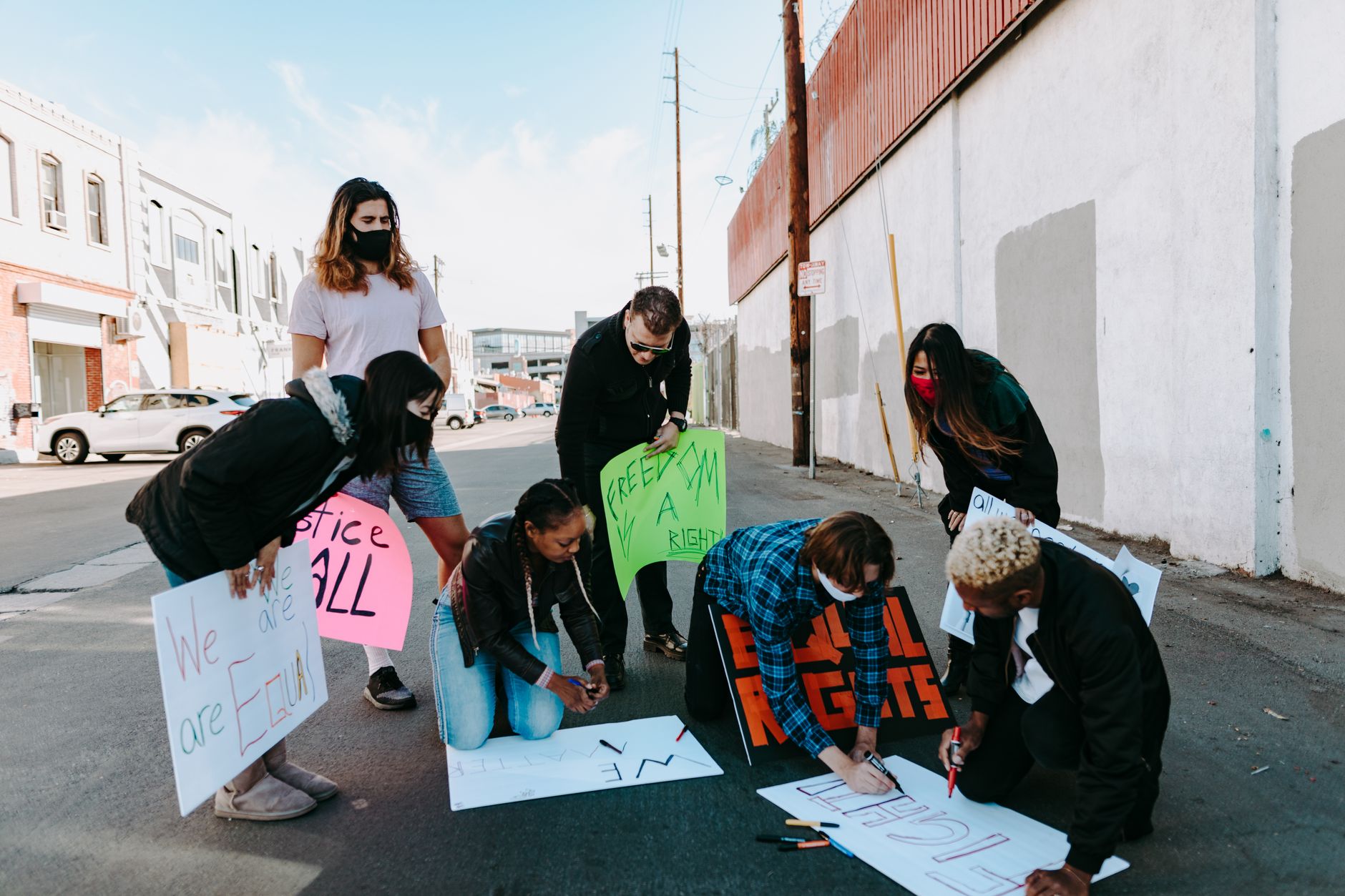 A group of diverse individuals preparing protest signs outdoors for a peaceful demonstration.