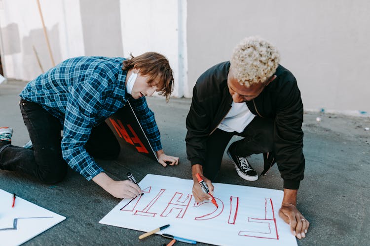 A Men Writing On A Poster Together