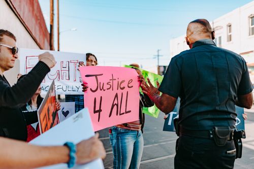 Free Police engaging with protesters holding signs for justice and peaceful rights. Stock Photo