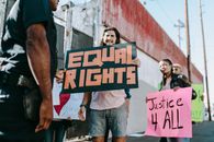 Woman in Blue T-shirt Holding Brown and Black Wooden Sign