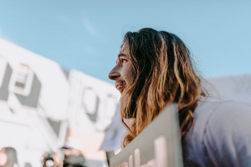 Free A man with long hair passionately engages in an outdoor protest, holding a sign. Stock Photo
