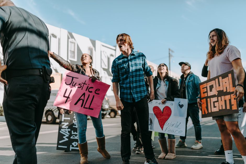 Diverse group of protesters holding signs advocating justice and peace in a peaceful rally.
