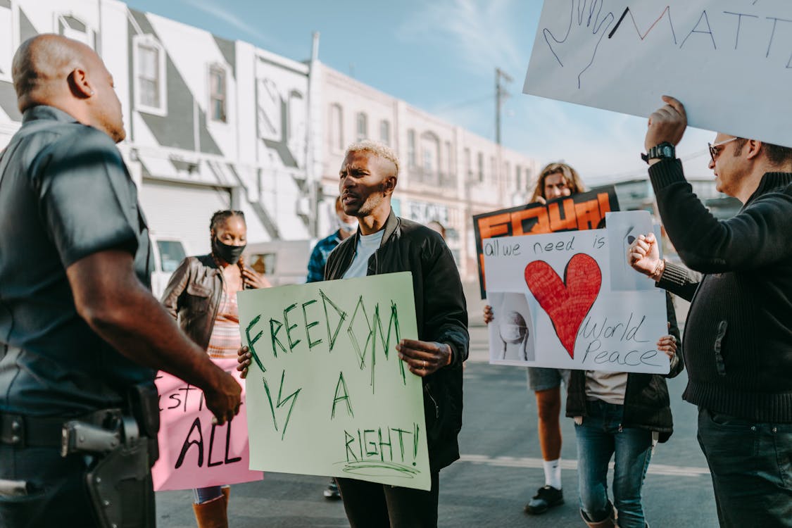 A Man Blocking the Rallyists Protesting on the Street · Free Stock Photo