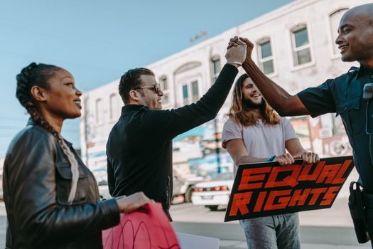 Diverse group of people participating in an equal rights protest outdoors, holding placards and engaging with police.