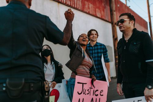 Free A diverse group rallies with signs at a peaceful protest outdoors. Positive interaction with police enhances community spirit. Stock Photo
