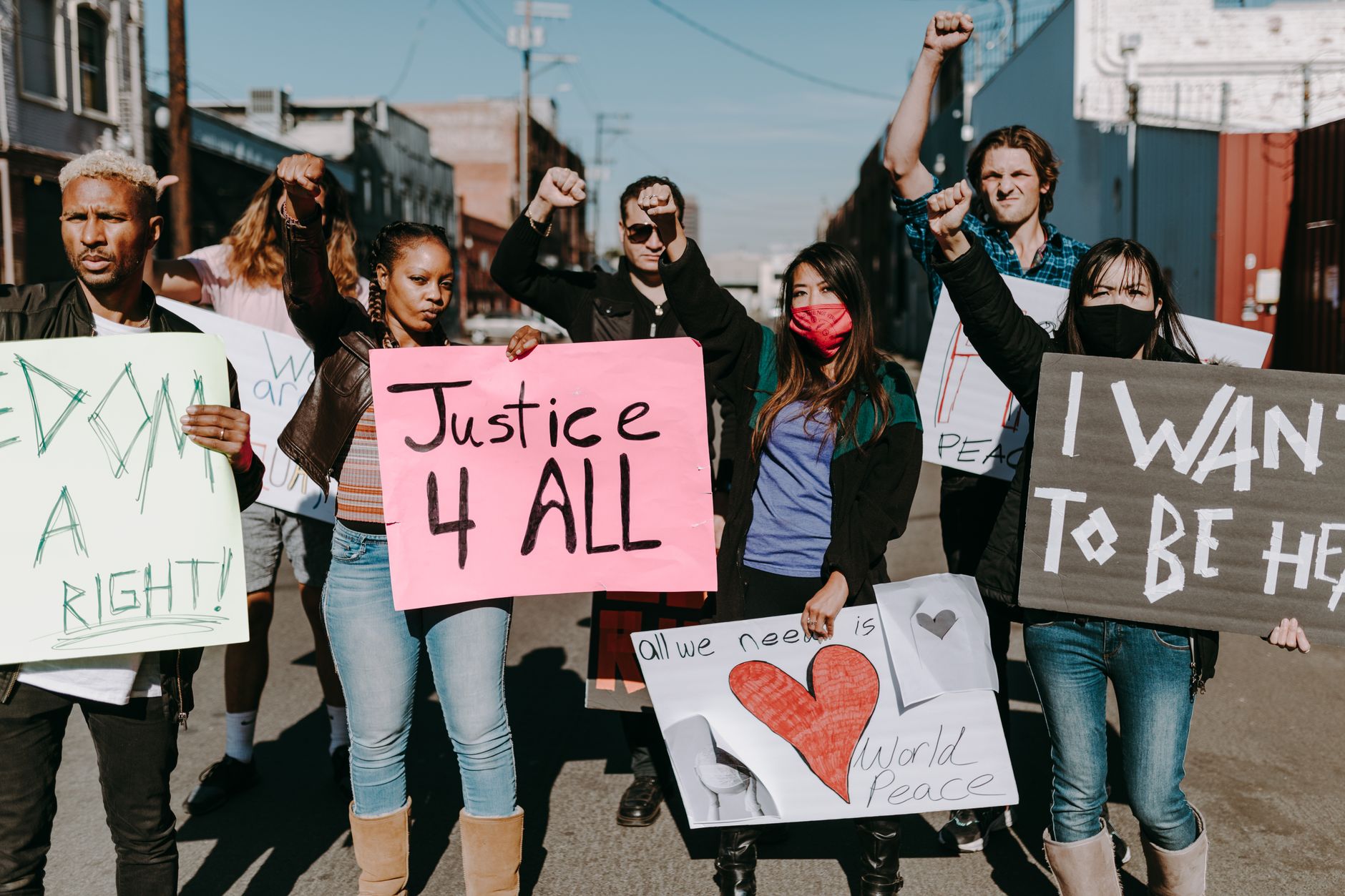 A diverse group of people holding protest signs for justice and equality outdoors.