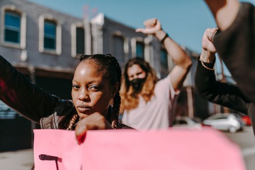 Free Group of diverse protesters raising signs and fists during a demonstration outdoors. Stock Photo
