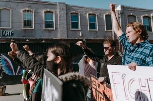 Free A diverse group of protesters raise fists with placards demanding equal rights outdoors. Stock Photo