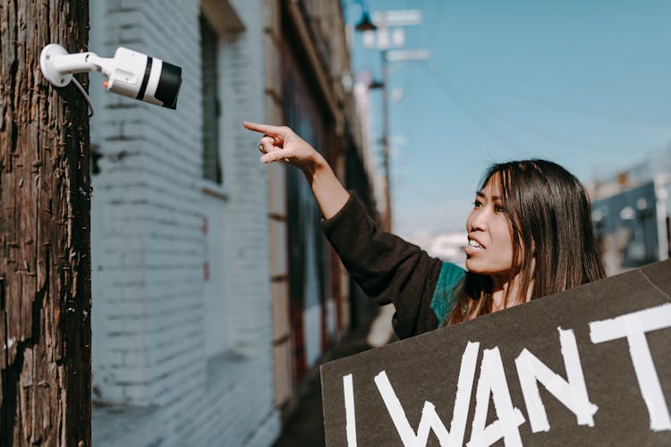 A Woman Pointing A Cctv