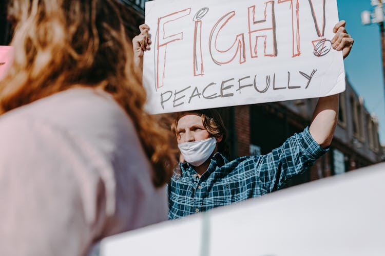 A Man Wearing Face Mask Holding Banner