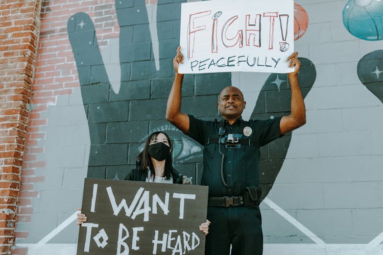 A Policeman And Woman Holding Protest Banners