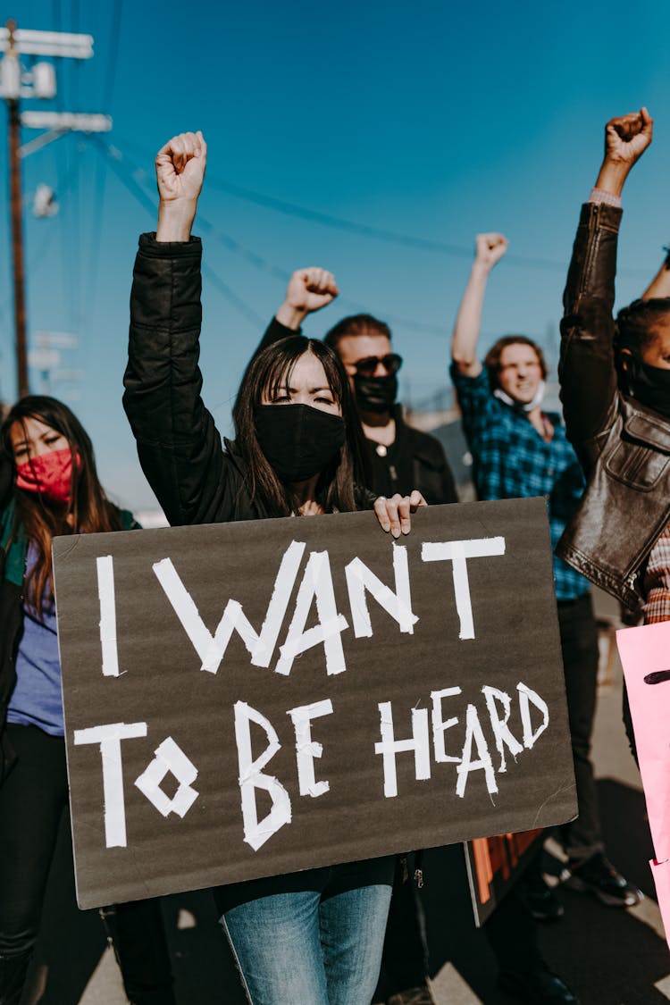 A Group Of People Wearing Face Masks While Protesting 