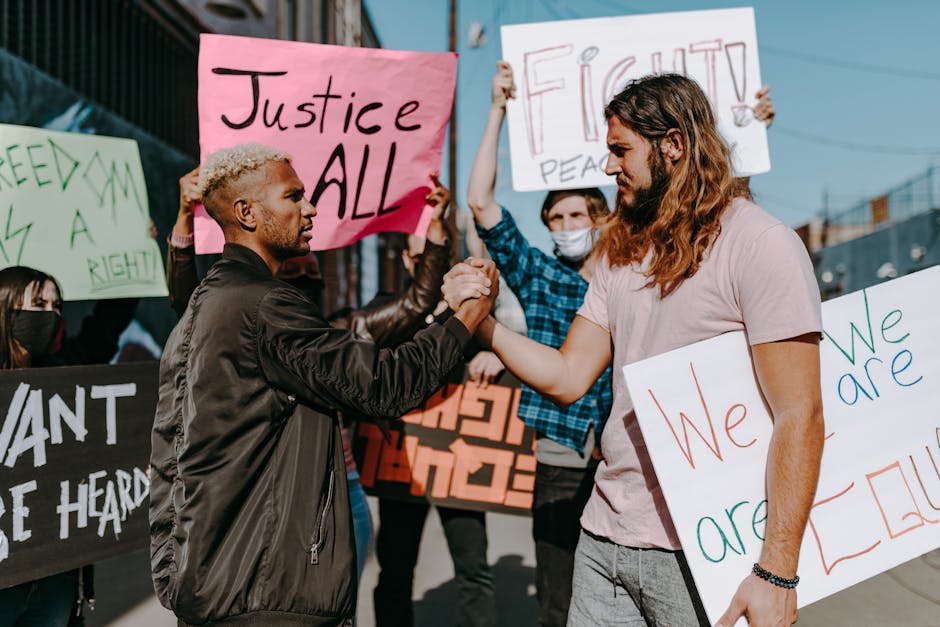 A diverse group of people at a demonstration holding signs promoting justice and equality.