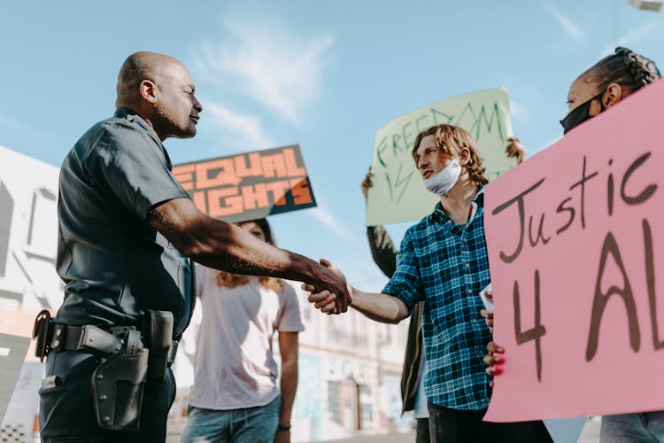 Police Offer Shaking Hands To A Student Protesting On Street