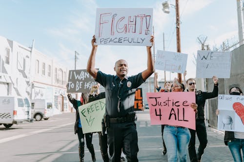 Man in Black and White Jacket Holding White and Blue Signage