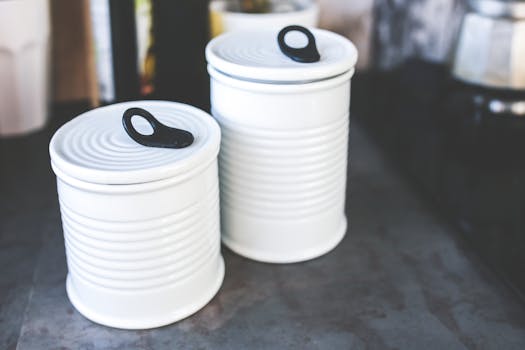 Two white ceramic canisters with lids on a kitchen countertop, enhancing storage and decor.