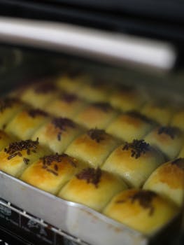 Golden brown pastries with chocolate sprinkles baking in an oven, capturing warmth and freshness.