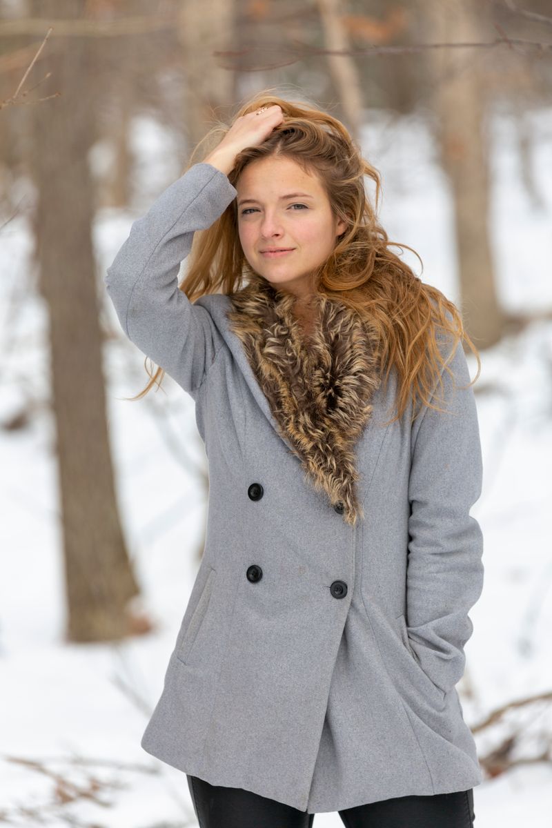 Young woman with red hair in a coat in snowy woods
