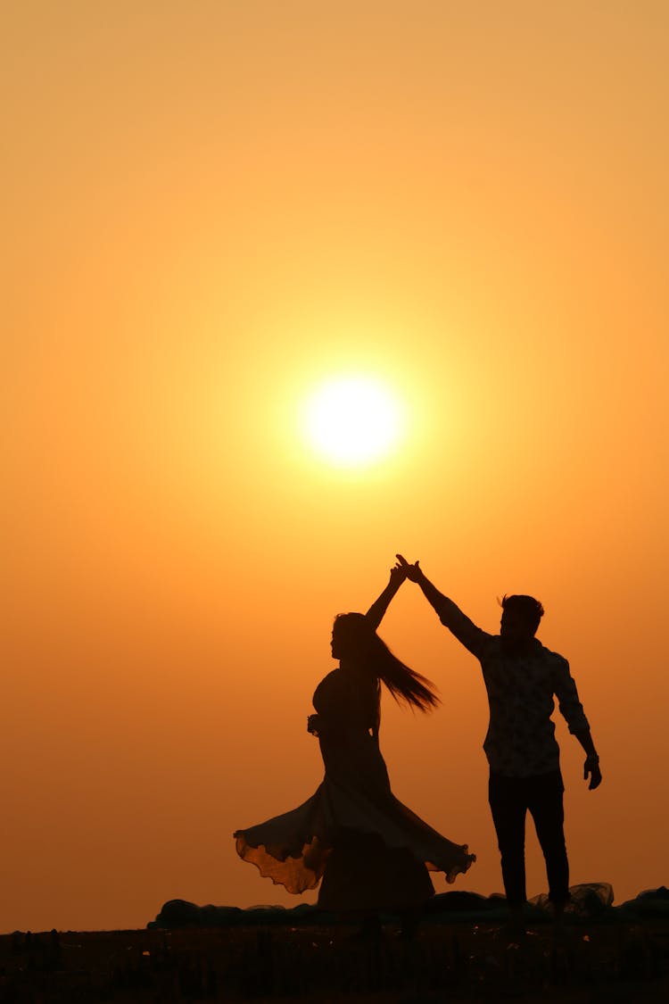 Silhouette Of Couple Dancing Together During Sunrise