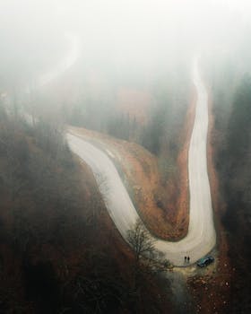 Aerial view of a foggy winding road in Düzce, Turkey, with misty atmosphere and sparse trees.