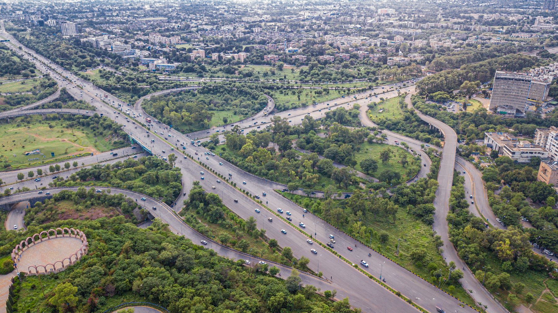 Aerial shot of Islamabad's intricate expressway system, showcasing lush greenery and urban development.
