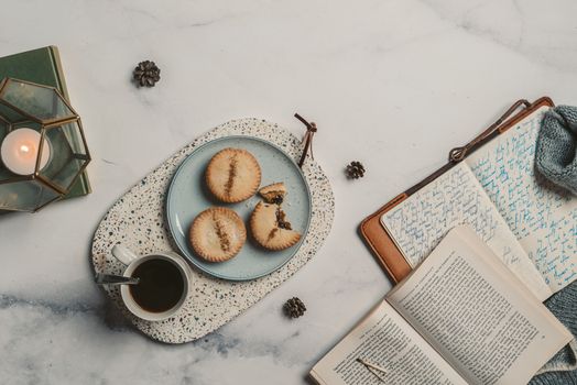 Warm flat lay featuring a cozy setup with coffee, cookies, and open journals on a marble surface.