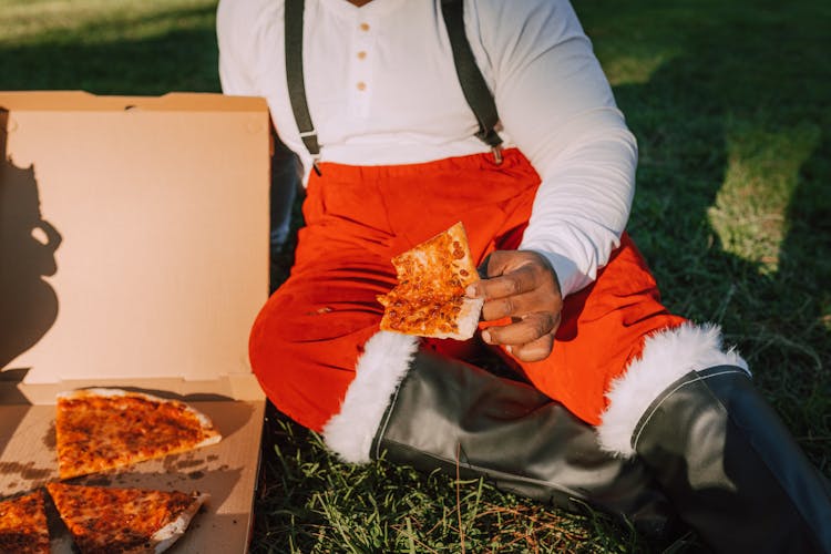 Man In Red Pants And Black Boots Holding A Pizza