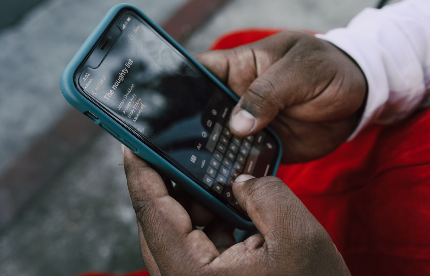 A person typing on a smartphone displaying a list titled 'The naughty list'.