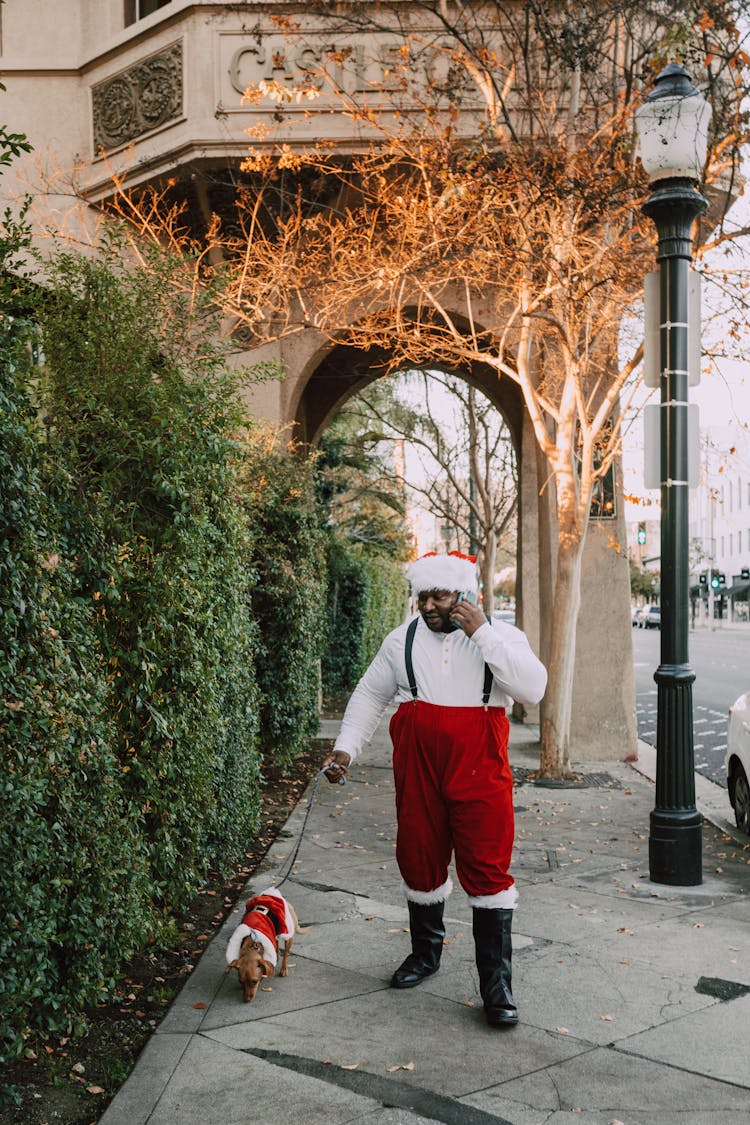 A Man Talking On The Phone While Walking His Dog