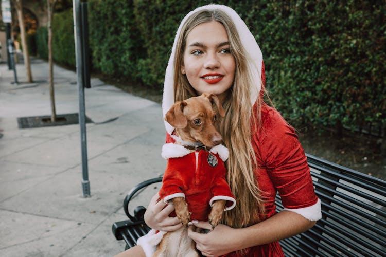 A Woman And A Dog In Costumes Sitting On A Bench