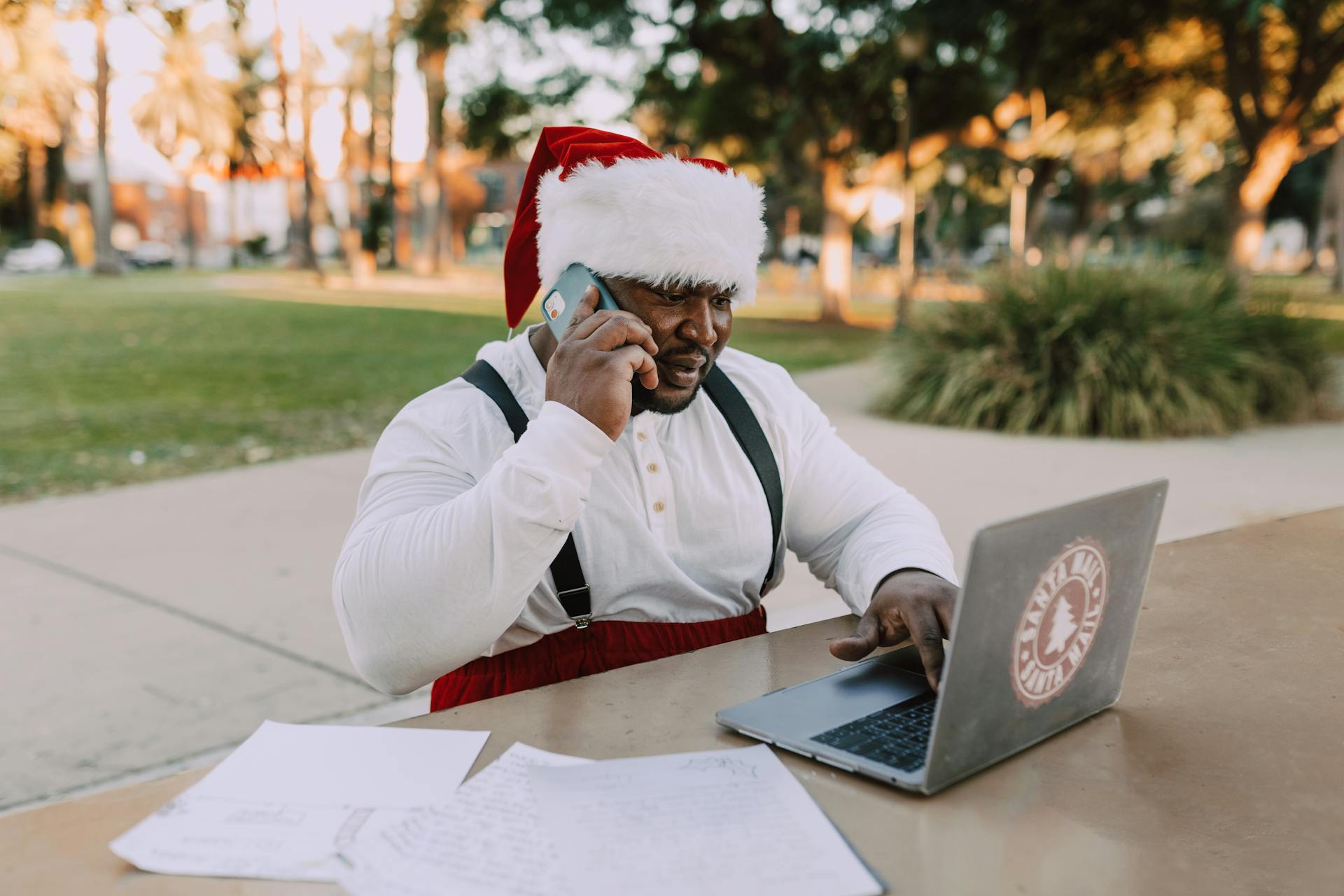 Man in White Long Sleeve Shirt Wearing Red and White Santa Hat Sitting on Chair