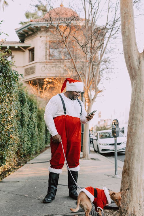 A Man Wearing a Santa Claus Costume with His Dog